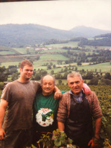 Three men standing in front of green hills