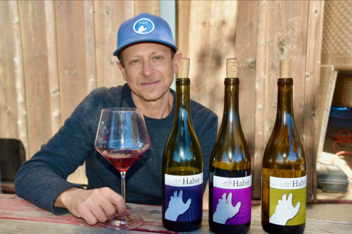 Jeff with three bottles of wines. Drinking a glass of Pinot Noir
