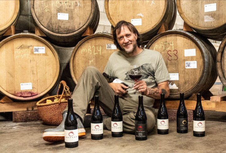 Winemaker Chris Williams in the barrel hall surrounded by bottles of Brooks Pinot Noir
