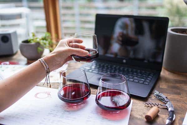 Woman with three glasses of red wine in front of laptop computer