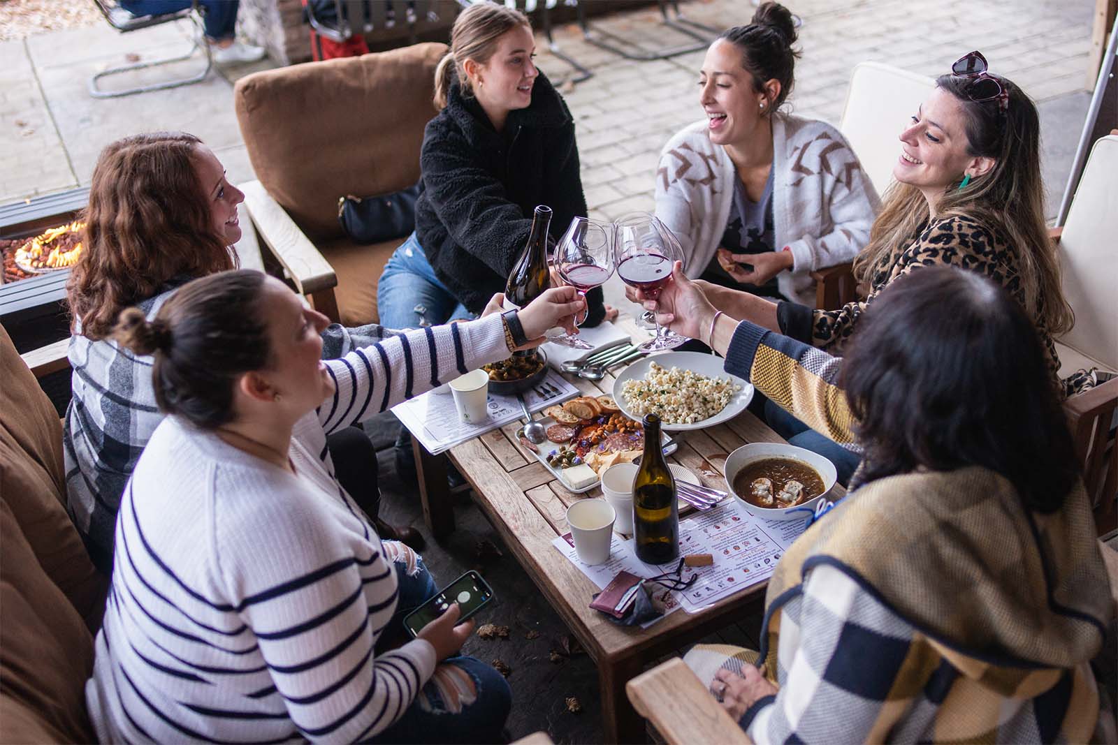 A group of young women raising their glasses at the lower patio table