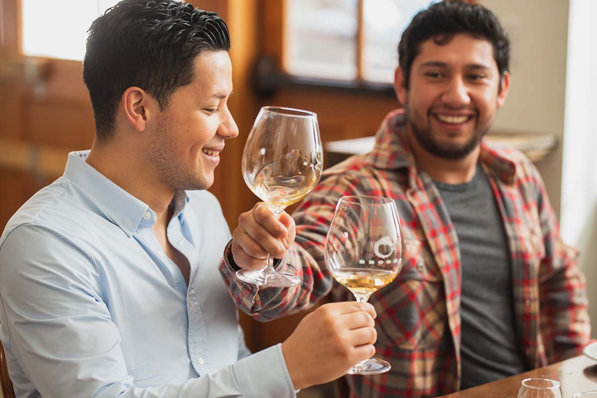 Two men drinking Brooks white wine and smiling