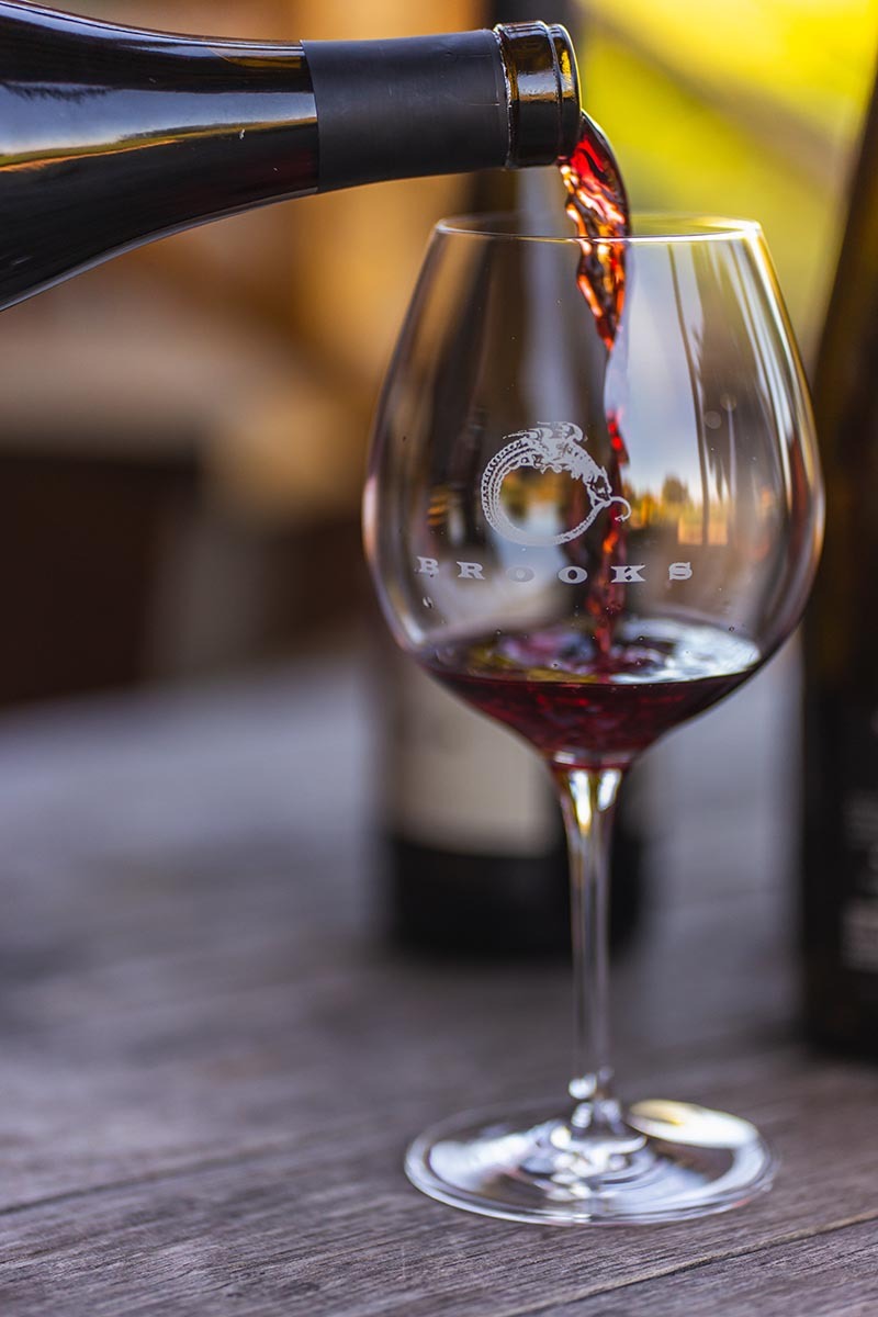 A glass of Pinot Noir being poured to showcase a light and elegant style from Brooks Winery in Willamette Valley, Oregon. 