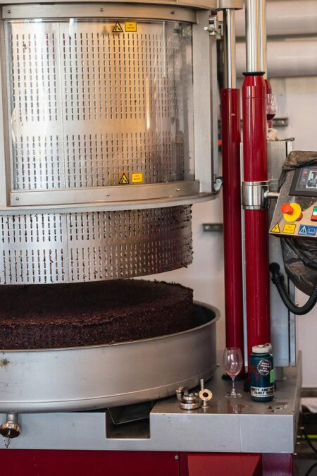 A close up of the perforated stainless steel basket lifting off a cake of grape skins after the basket press has pressed the juice from the grapes for wine making. 
