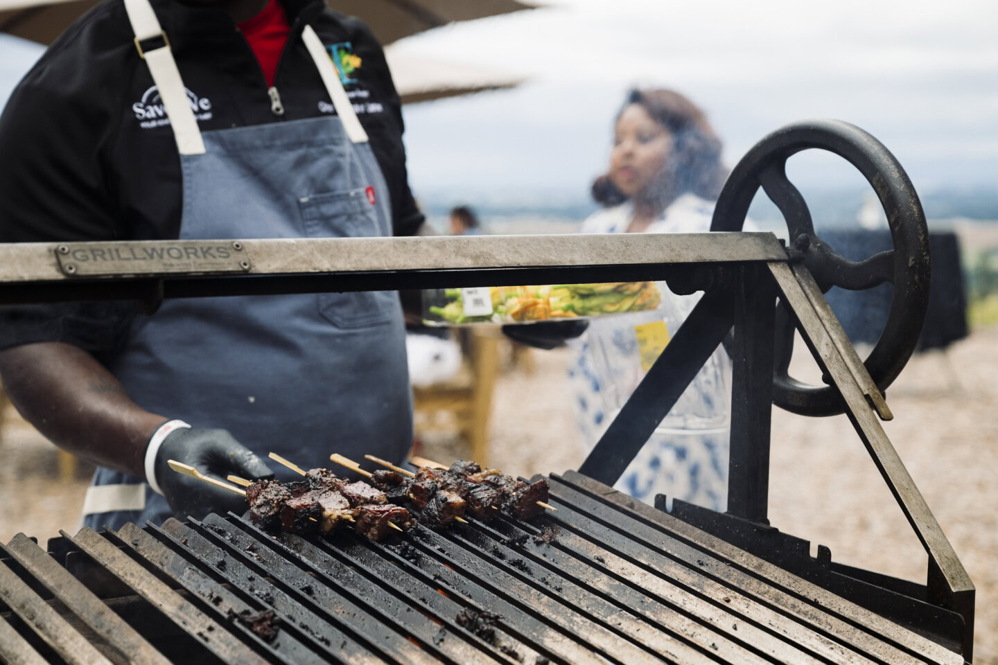 A grill master expertly prepares kebobs at a summer BBQ .