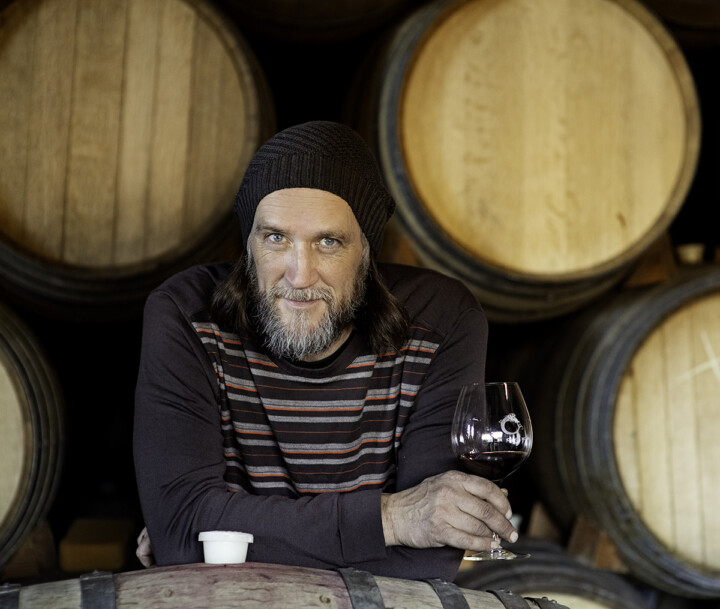 Winemaker Chris Williams holding a glass of Brooks Pinot Noir in the barrel hall.