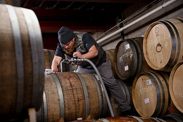 A winemaker at Brooks Wine tops off a barrel of wine with more wine after it has experienced evaporation during secondary fermentation. 