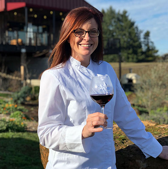 Chef Norma in front of the Brooks Tasting Room holding a glass of Brooks Pinot Noir
